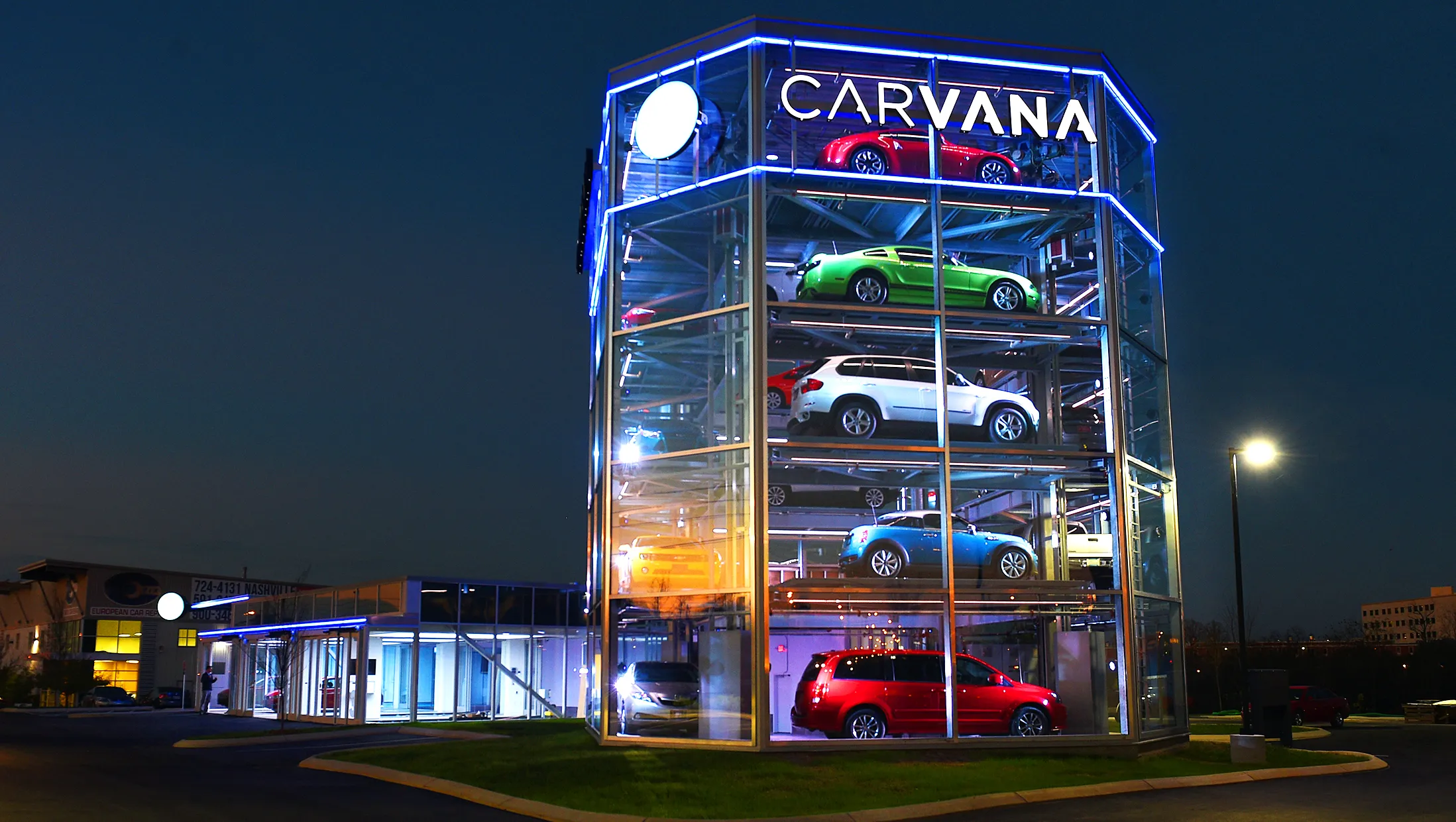 Photo of a Carvana car silo lit up at night.