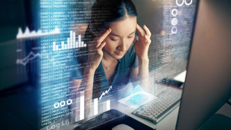 Image of young woman experiencing information overload from technology.